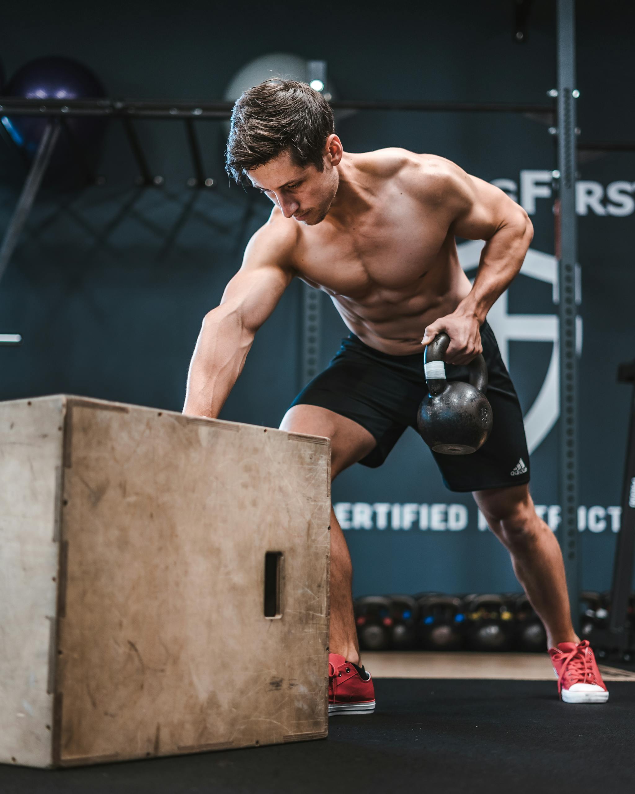 Athletic man working out with a kettlebell, showcasing strength and fitness indoors.
